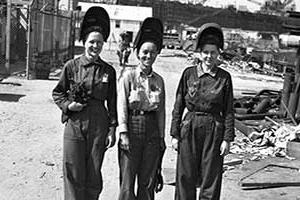 历史上有三位女性穿着工作服戴着头盔微笑着.